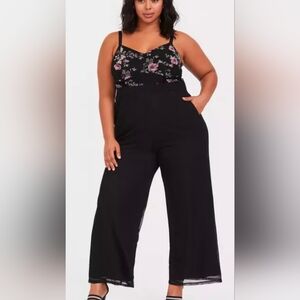 This is a Torrid black floral wide leg challis jumpsuit with a mesh overlay on t